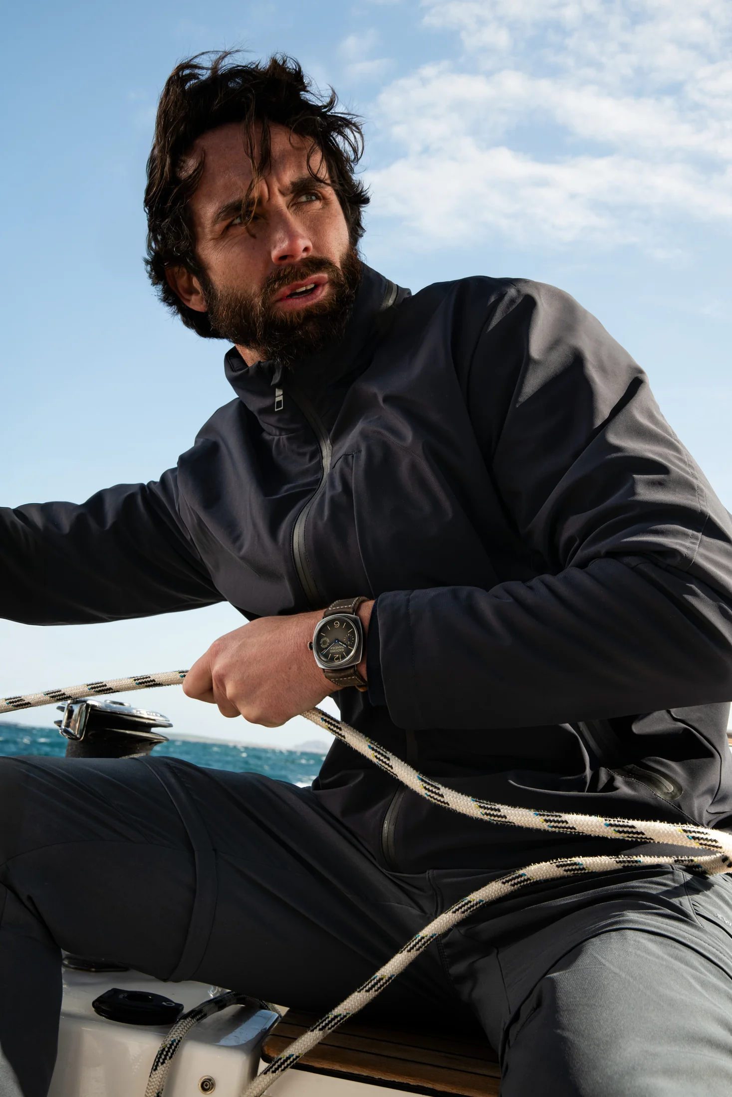 Sailor holding a rope aboard a boat with a Panerai watch on the wrist.