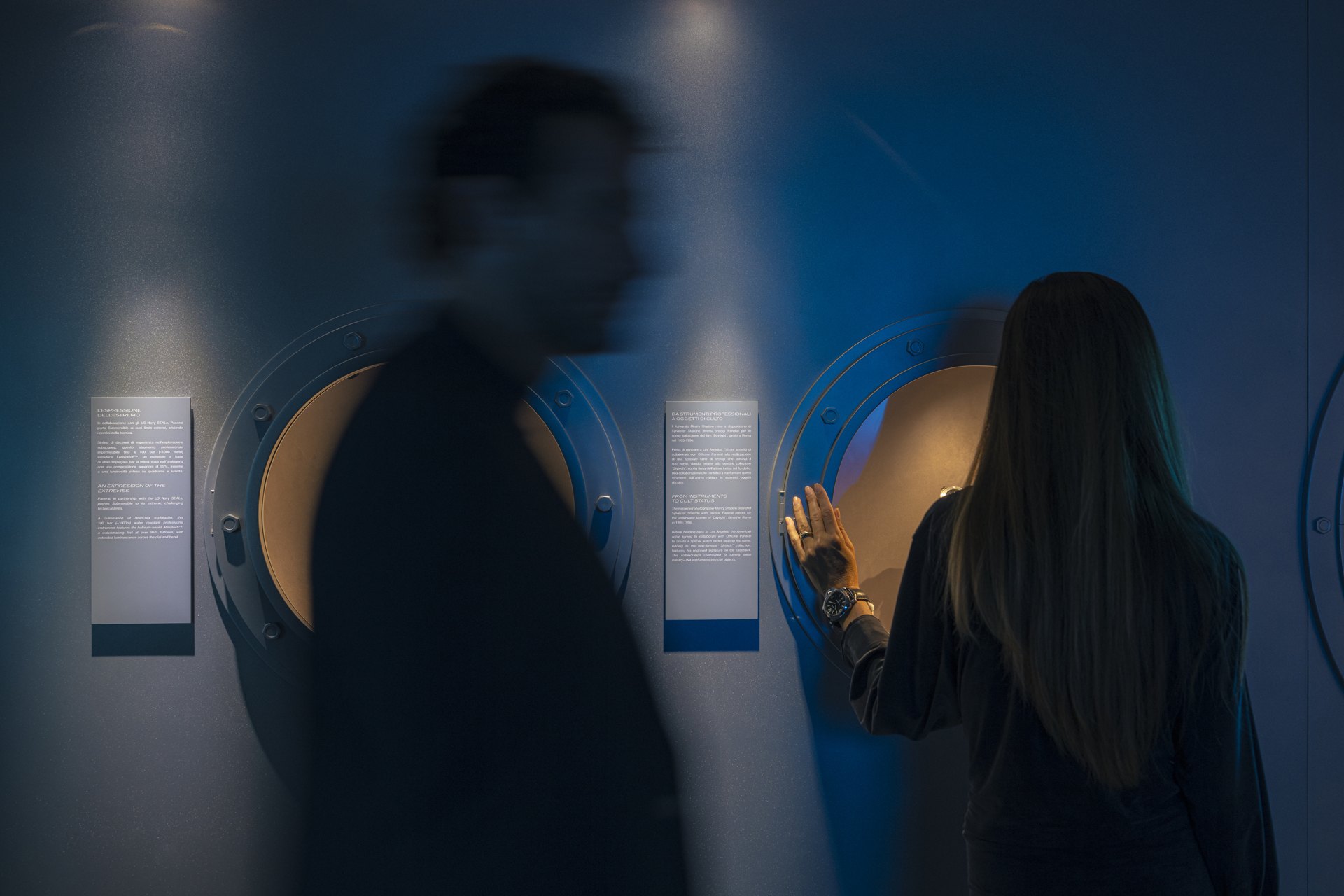 Visitors exploring the blue-lit porthole displays at Immersion